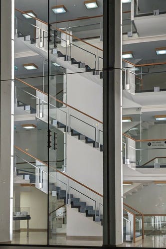 Stairs going up several floors, seen from the outside through a glass wall. One can read "studio 104" with an arrow.