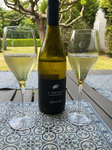 Deux verres de vin blanc et une bouteille de l’Instant Chardonnay de chez Berthier. 