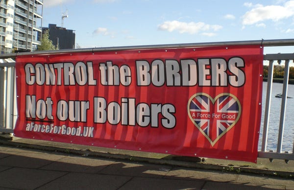 A red banner on a bridge fence, with a hear shaped uonion jack and in white writing:
Control the borders not our boilers. 