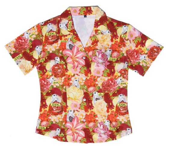 A photograph of a Hawaiian style button-up shirt, in women’s cut, featuring a field of tropical flowers with an eagle and the words “oh my god, what the fuck” amongst the pattern.
