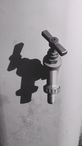 Black and white photo of a water tap on a mooring post by the Union Canal, strong sunlight on it, casting a sharp shadow of the faucet to the left of it