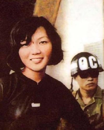 Cette photo a été prise par un journaliste japonais à la sortie du tribunal. Elle représente Võ Thị Thắng sui sourit, devant un soldat patibulaire. 