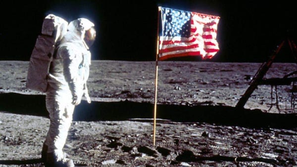 American flag on a pole with a top bar preventing it from sagging or twisting. And it’s on the moon next to, like, an astronaut.