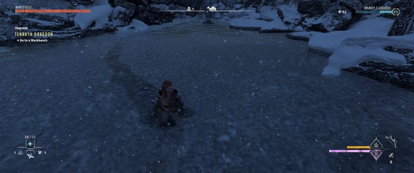 Screenshot of Aloy walking through a pond during a blizzard. A layer of wet snow is floating on the surface of the pond, and a trail is visible through the snow from where Aloy has walked.