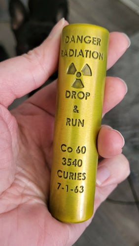 Metal prop, a yellow/gold cylinder stamped with "Cobal 60, drop and run" and a radiation symbol