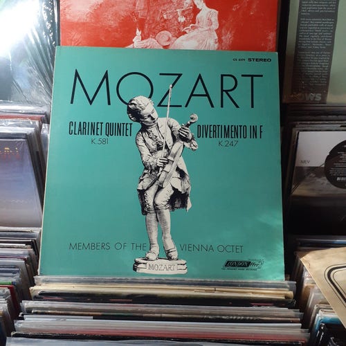 Turquoise blue album cover features an illustration of a statuette of Mozart as a child, holding a violin.