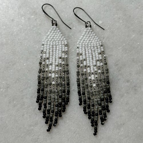 White to black ombre Native beaded fringe earrings on a marble background