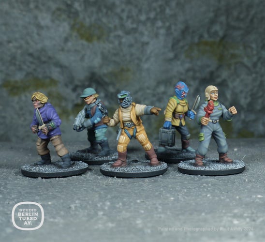 wargame models. five space/sci-fi crewmembers. One is an anlien-ghoul with blonde hair and wears a purple top and mid-brown tactical trousers. She holds a knife. The second is wearing an aqua green hat and matching trousers with a mid-blue tunic and brown sleevless jacket. She hold a white space rifle. The third wears a gasmask helmet and wears an off-white top with orange sleevless jacket and trousers. The forth in a blue-tone alien with pink veins. she wears a yellow top with grey trousers and carries a white brief case. The fifth is wearing a grey mechanics boilersuit with off-white cap and holds a red wrench.