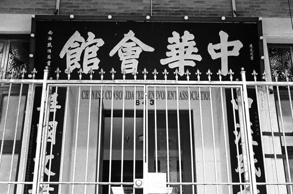 a photo of a big sign in chinatown in a large chinese brush script that says chinese assocation