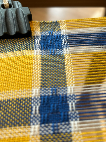 Close up of huck lace pattern in a yellow, blue and white checked handwoven teatowel in progress