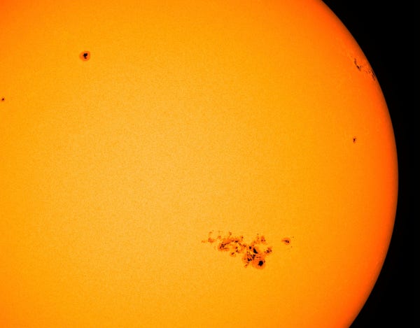 Das aktuelle Bild des Satelliten SDO zeigt die erdzugewandte Seite der Sonne in gelber Farbe. In dieser Darstellung ist die Oberfläche nahezu glatt und man erkennt darauf mehrere dunkle Sonnenflecken.