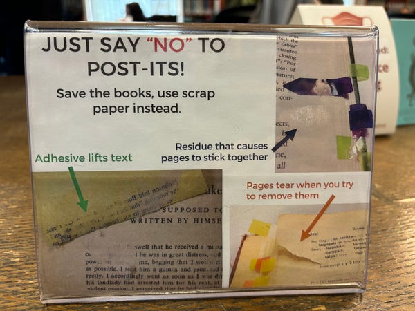Tabletop sign “Just say no to post-its “ showing some of the damage they can do in library books.