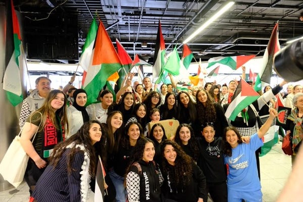 The team poses for a picture, surrounded by large Palestinian flags