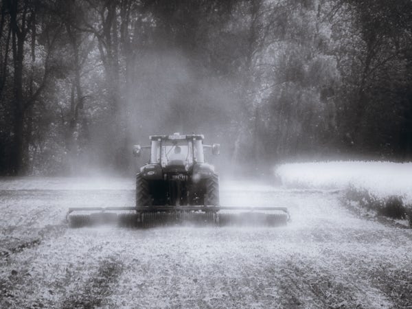 Schwarzweissfoto eines Traktors, der ein Feld pflügt/eggt/wasauchimmer