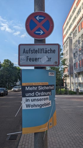Eine Wahlplakat der CDU, dass für mehr Ordnung wirbt. Hängt an einer Laterne mit zwei Verkehrszeichen (absolutes Halteverbot mit Hinweis auf Stellfäche für Feuerwehr)