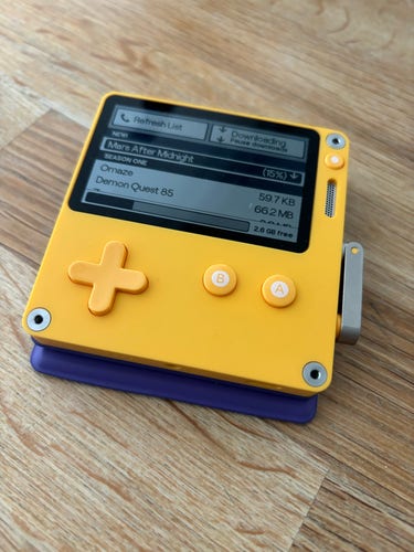 Play date portable console. Showing the download screen. The top item shows the game “mars after midnight” downloading. There are another two games on the list “Omaze” and “Demon Quest 85”