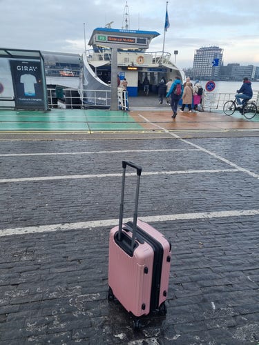 Suitcase in front of the Amsterdam ferry on its way to the airport