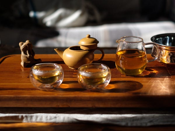 tea tray with sheng puerh in glass cups and pitcher; sunlight caustics from copper bowl and glassware