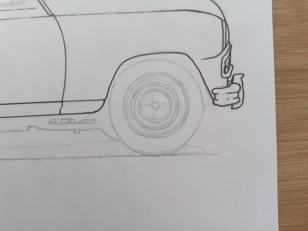 A close up photograph of an illustration in progress.  Pencil sketch and preliminary ink lines mark out the front of an old car.