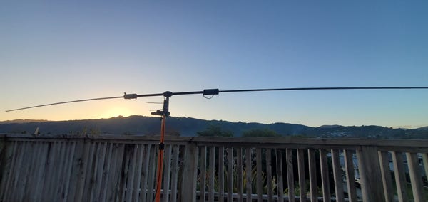 Buddipole antenna setup against a clear sky, sun setting in background 