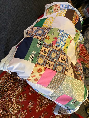 Multicolored patchwork quilt on a chair with a traditional patterned carpet in the background.