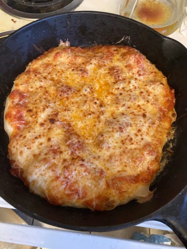 A freshly cooked cheese pizza in a cast iron skillet