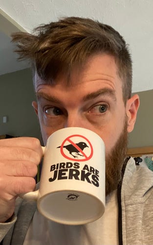 A disheveled Zach drinks out of a Birds are Jerks mug