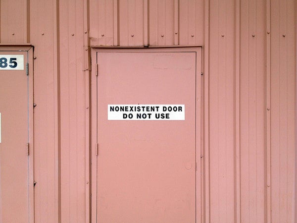 a pink wall with the outline of a door in it with a sign on it that says "nonexistent door do not use."
