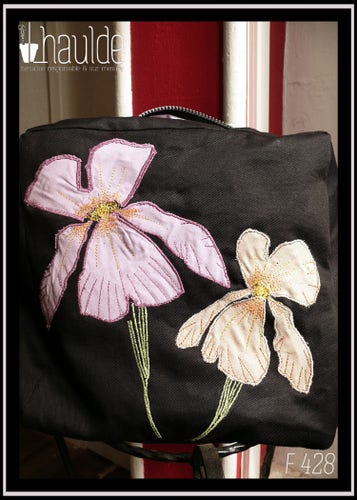 sac en sergé noir format carré à bandoulière avec des appliqués mauves et beiges en forme d'iris, le centre des fleurs et leurs pétales sont brodés à la machine ainsi que les tiges