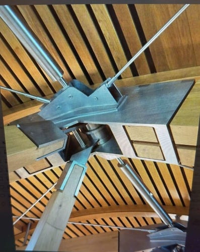 Foto di un architrave in  legno e metallo, fatta da sotto, in un edificio moderno dall architettura complessa. Il tetto è di legno a listarelle