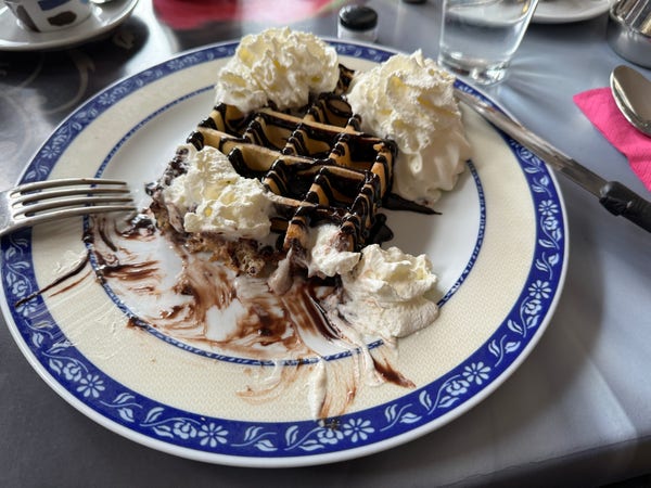 Photo of a waffle covered in whipped cream and chocolate