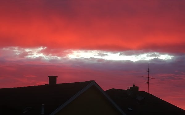 Par dessus les toits, lever de soleil rouge flamboyant.