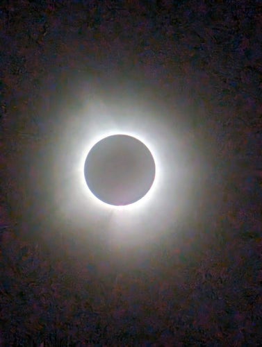 A black circle where the sun should be with a white glow from behind it