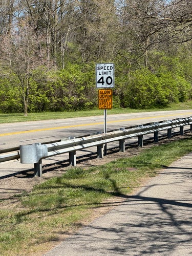 A speed limit sign with signs below it saying “Slow down. Obey speed limit”
