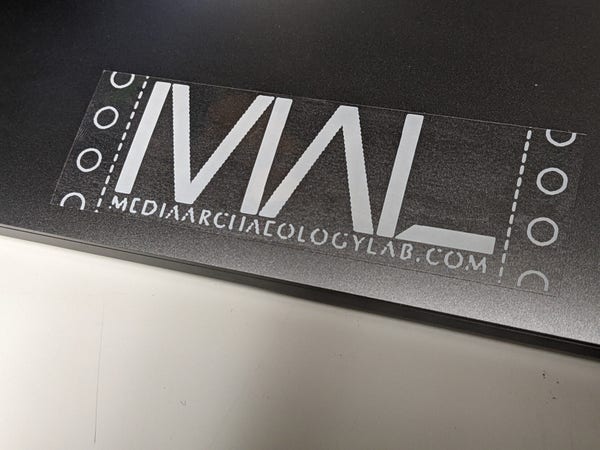 white on clear MAL logo sticker with faux tractor feed paper edges 